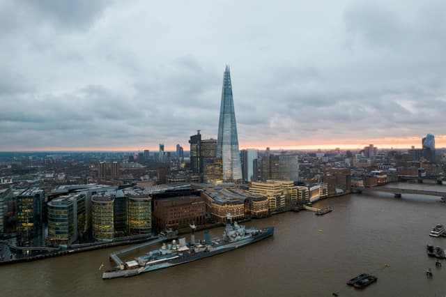 A beautiful cityscape of London showcasing The Shard and River Thames under an overcast sky at sunset.