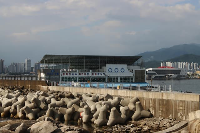 Modern waterfront scene with concrete tetrapods and city skyline.