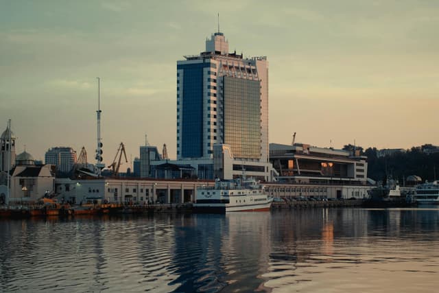 Scenic view of Odesa Sea Port and modern architecture reflecting in water during sunset.
