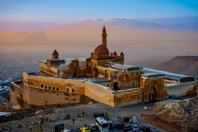 Ishak Pasha Palace in Turkey under a dramatic sunset, showcasing ancient architecture.