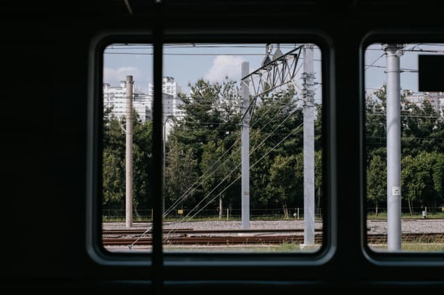 Urban view captured from a train window in Chuncheon, showcasing tracks and city buildings.