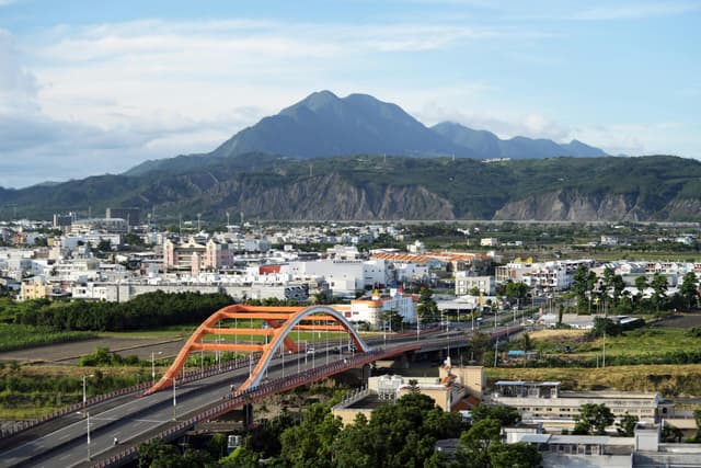 Explore the vibrant skyline of Taitung City with its iconic bridges and majestic mountains.