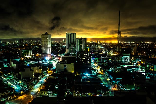 Stunning night view of Quezon City skyline with illuminated buildings and vibrant city lights.