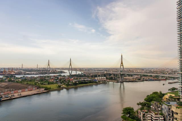 Aerial view of Bhumibol Bridge over the Chao Phraya River in Bangkok, highlighting the city's urban landscape.