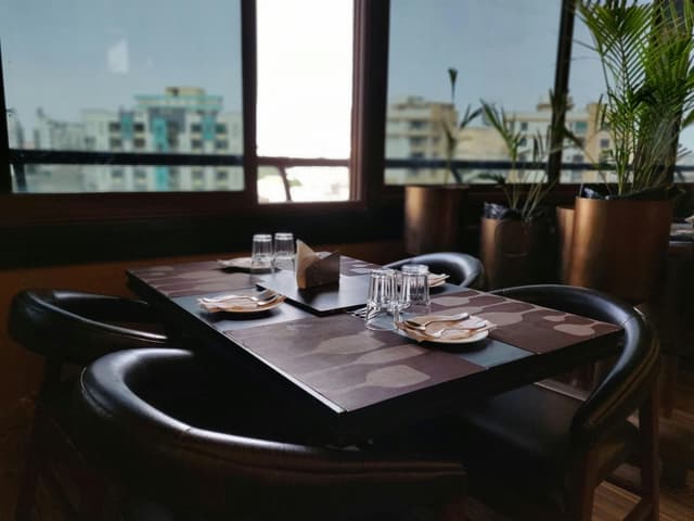 Elegantly set dining table in a modern restaurant with cityscape view, Jaipur.