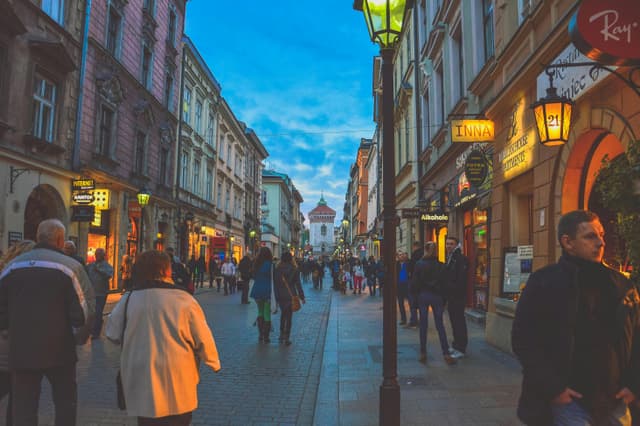 Bustling European street with historic buildings and evening shoppers under the vibrant dusk sky.