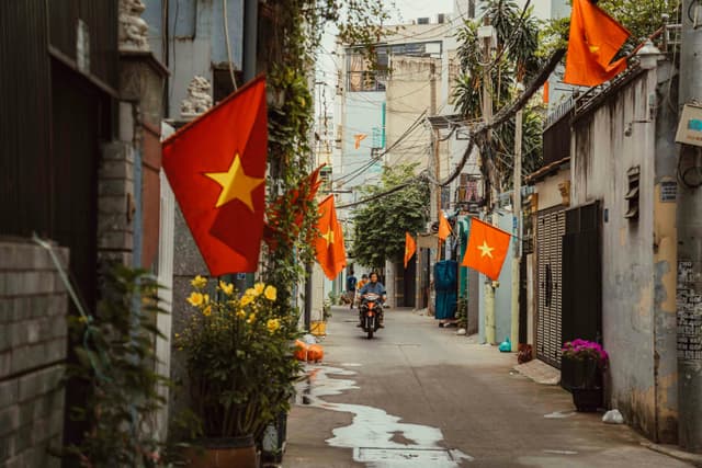 A vibrant alleyway in Ho Chi Minh City adorned with Vietnamese flags and lively surroundings.