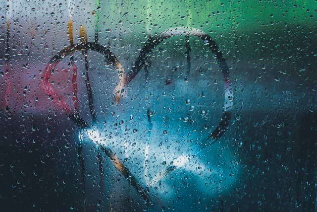 Window with raindrops and a heart drawing, capturing a romantic mood.