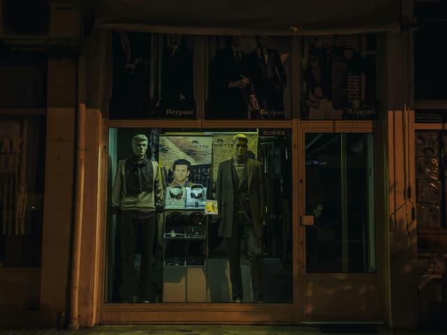 Illuminated storefront display with mannequins at night in Arhavi, Türkiye.
