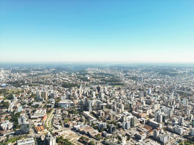 Stunning aerial view of Caxias do Sul's urban cityscape under a clear blue sky.