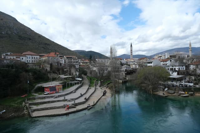 Charming landscape of Mostar in Bosnia Herzegovina featuring river, mountains, and skyline.