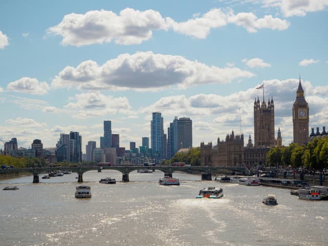 Scenic view of London's River Thames featuring Big Ben, city skyline, and boats on a sunny day.