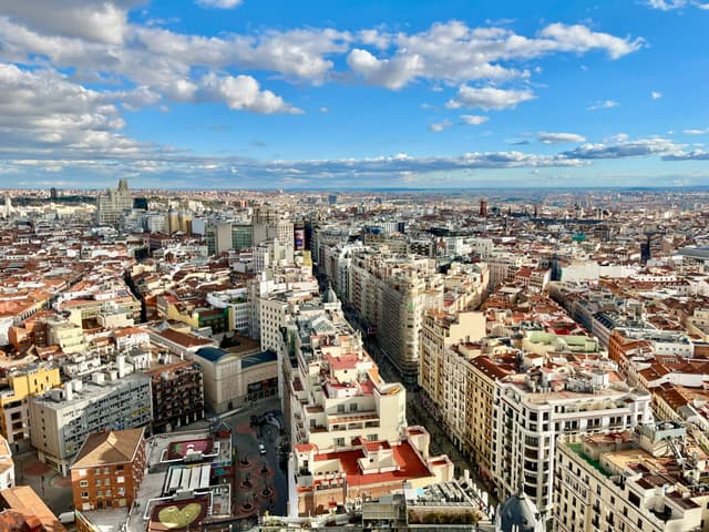 Stunning aerial view of Madrid's skyline with vibrant cityscape under a blue sky.