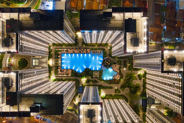Aerial view of illuminated modern urban complex with pool in Banten, Indonesia at night.