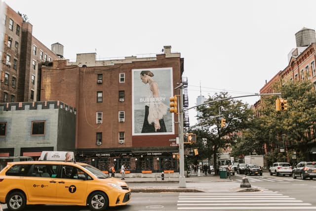 Vibrant street view in New York City featuring a Burberry advertisement on a brick building.