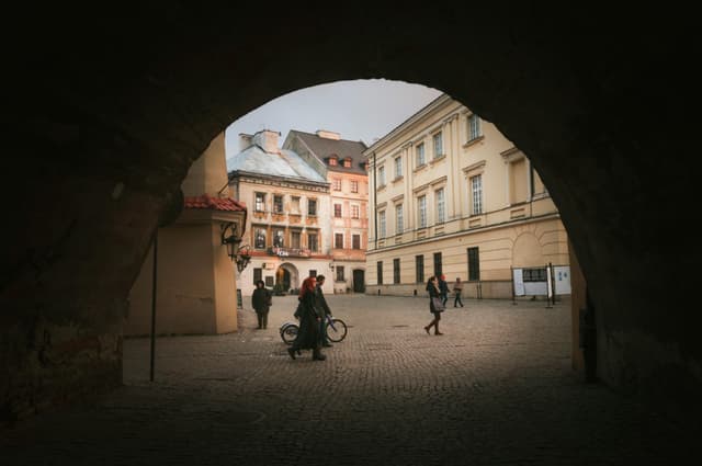 A historic street in Lublin, Poland, framed by a stone archway capturing daily life.