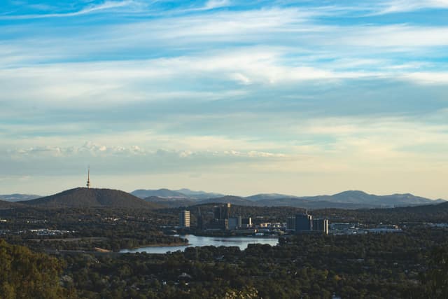 A scenic aerial view of Canberra highlighting Telstra Tower and surrounding landscape under a blue sky.