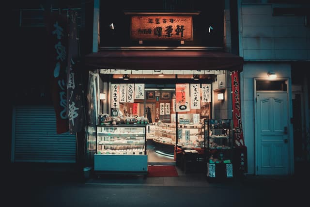 Illuminated traditional Japanese storefront in Kyoto featuring banners and signage at night.