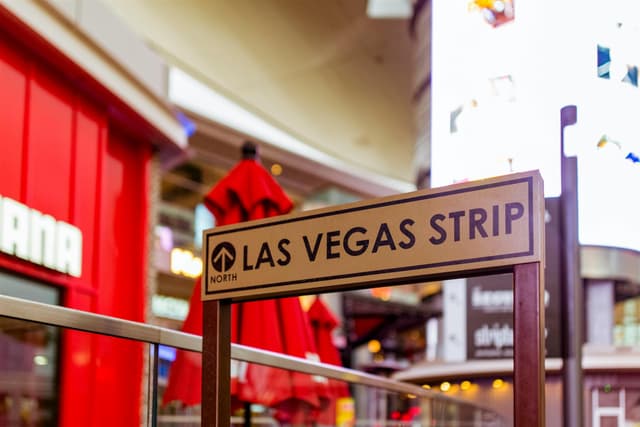 Iconic Las Vegas Strip sign with vibrant city life background.